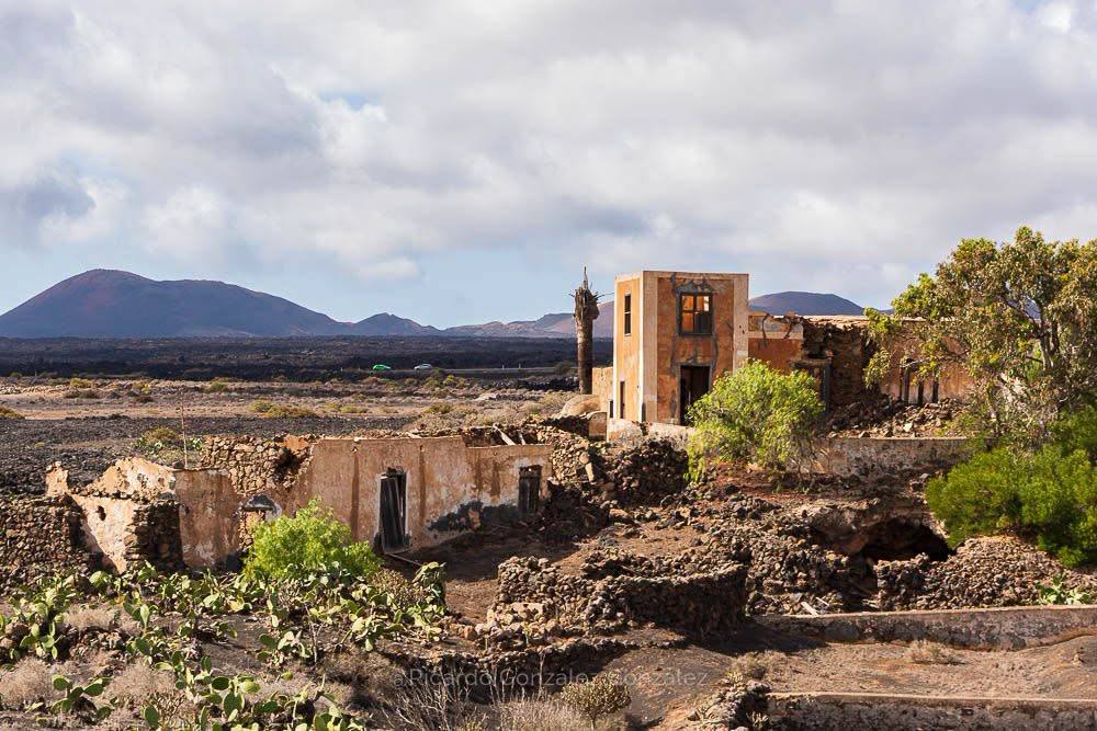 The existing ruin on the plot: lime-rendered walls, a two-storey tower still standing, a collapsed roof in the lava field